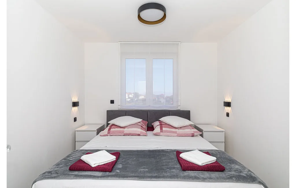 Un dormitorio con una cama doble bajo una ventana y toallas dobladas sobre la cama.