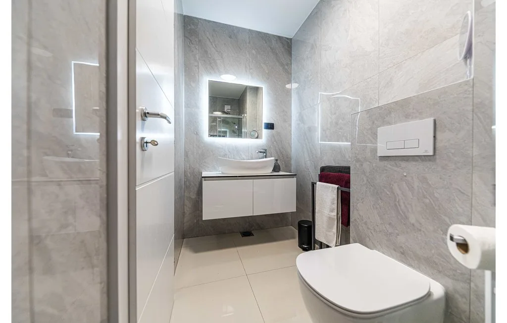 Un baño moderno con lavabo suspendido e inodoro.