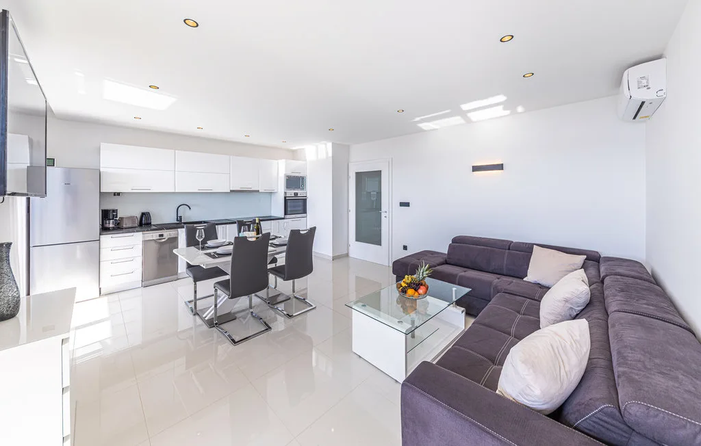 An open-plan living room with a kitchen, dining table, and sectional seating.