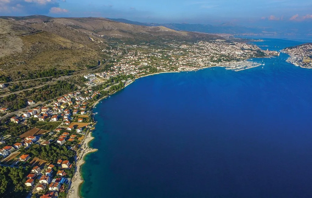 Una vista aérea muestra un pueblo costero que rodea una amplia bahía azul.