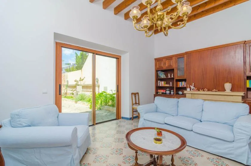A bright living room with pale seating, a round coffee table, and an open glass door.