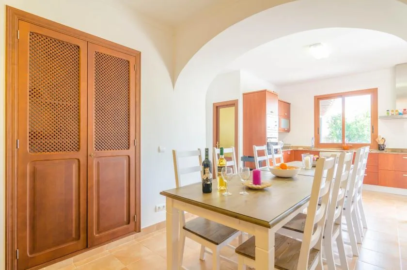 A dining area with a long table and chairs beneath a white arch.