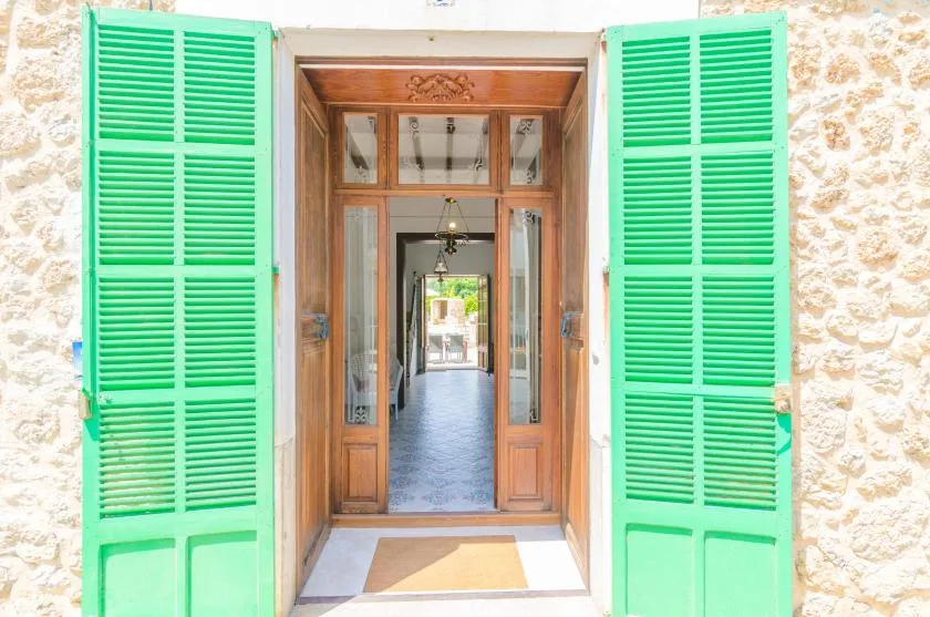 An open wooden doorway with bright green shutters leads into a hallway.