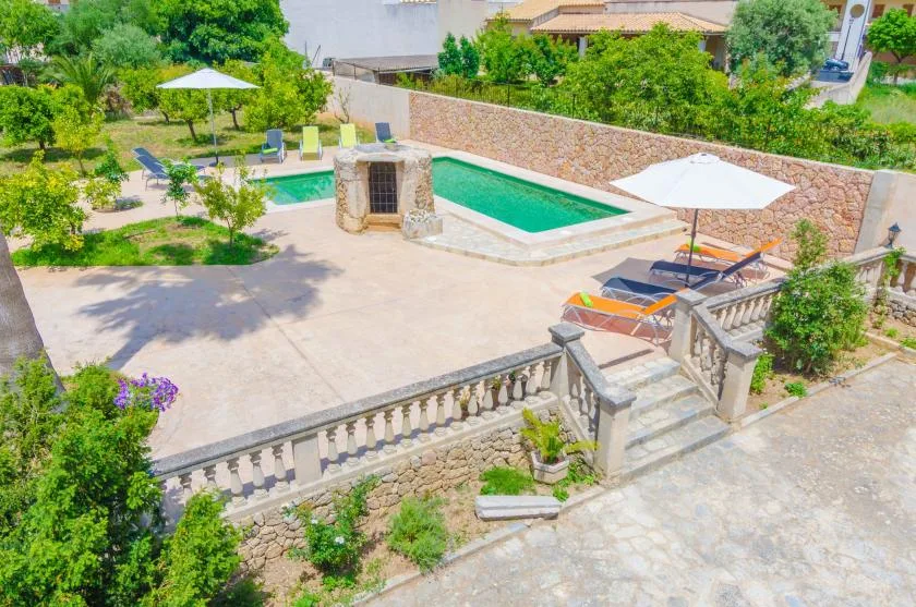 A landscaped pool patio with lounge seating, umbrellas, and stone steps.