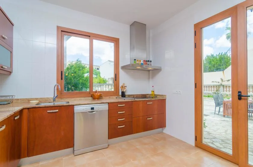 A kitchen with wood-toned cabinets and a glass door opening to a patio.