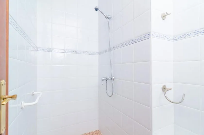 A tiled bathroom shower with a wall-mounted handheld showerhead.