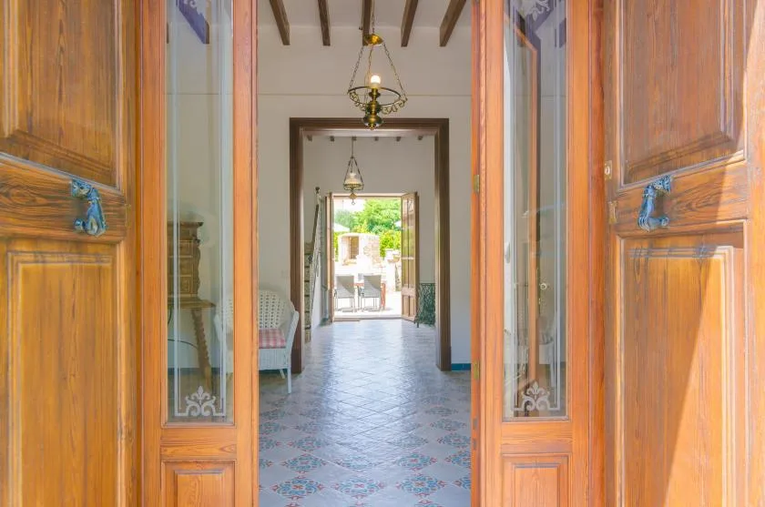 An interior hallway with patterned tile flooring and an open doorway at the far end.