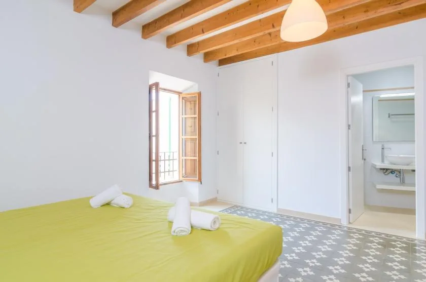 A bedroom with a green bedspread and an open doorway to the bathroom.