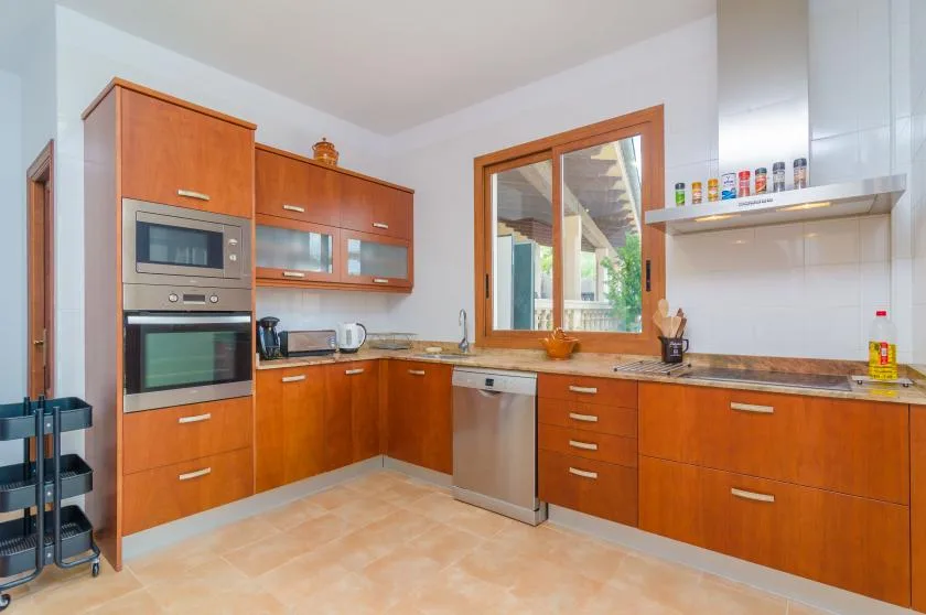A kitchen with wooden cabinetry, a countertop, and a window above the sink.