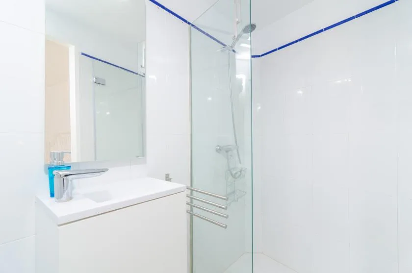 A bright bathroom with a sink and a glass shower.