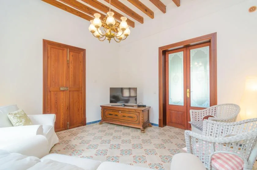 A bright living room with seating, a television, and wooden doors.