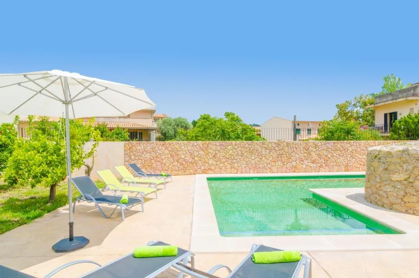 A sunny outdoor pool area with lounge seating and a large umbrella.