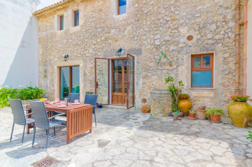 Un patio de piedra con una mesa de comedor al aire libre y plantas en macetas.