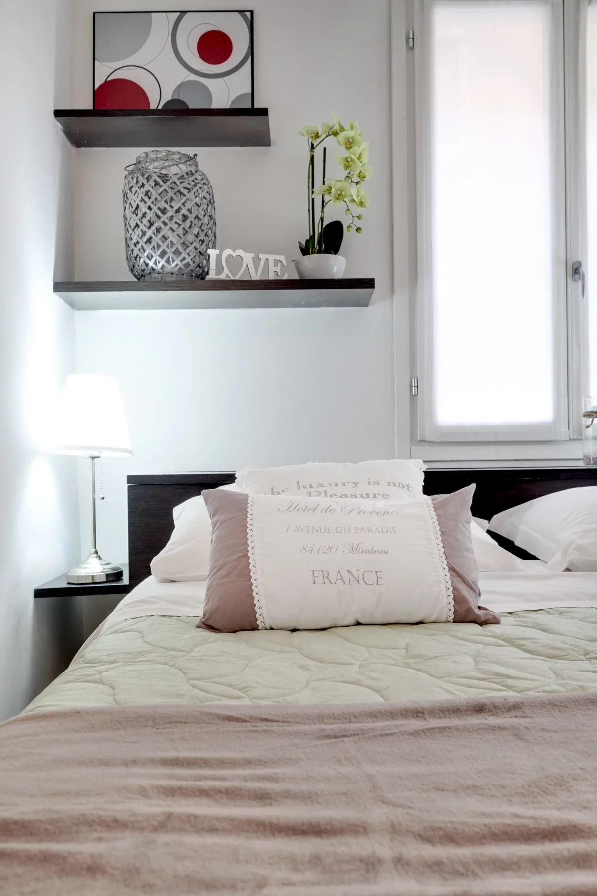 Un dormitorio con una cama bien hecha y estantes flotantes en la pared.