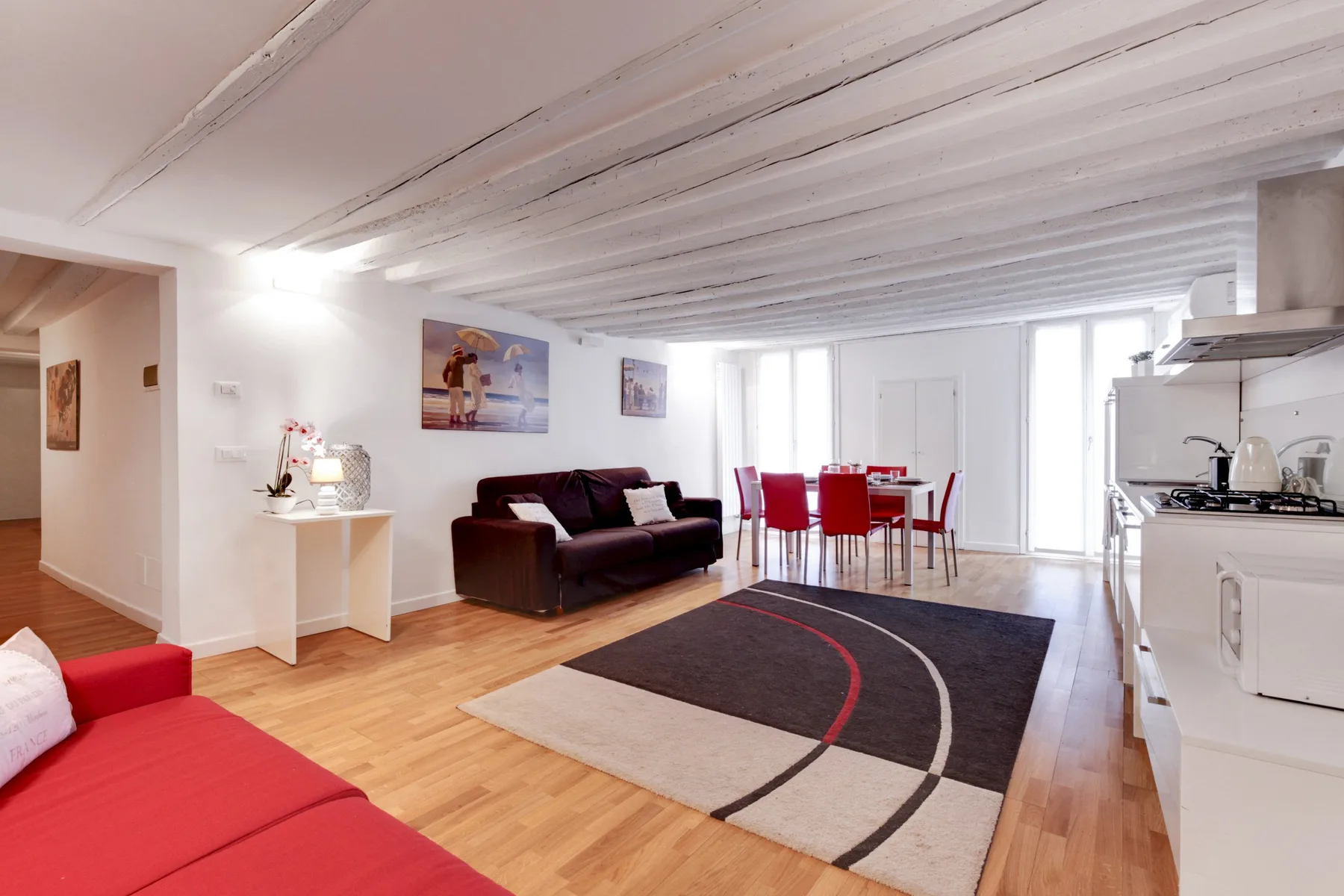 Una sala de estar y comedor de concepto abierto, con asientos rojos y una alfombra oscura.
