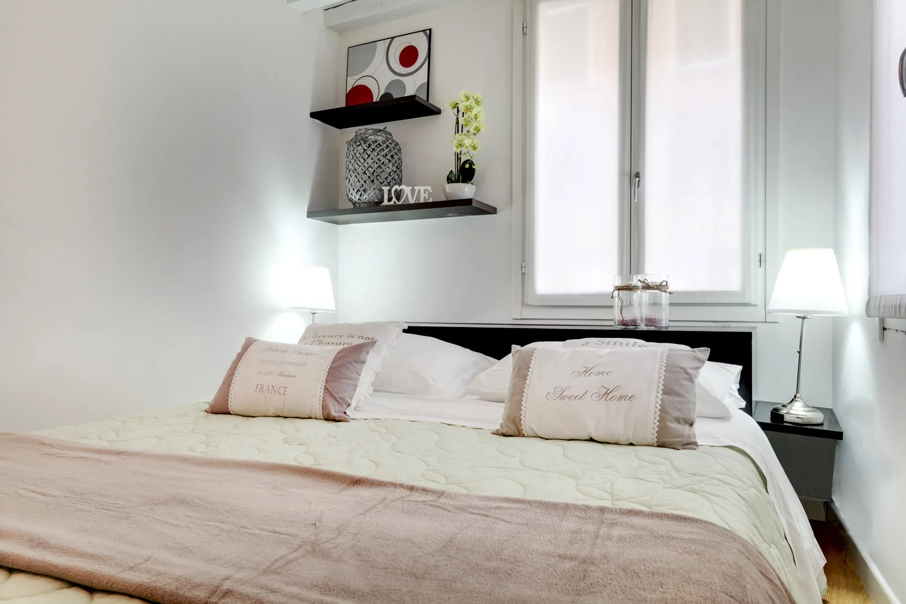 Un dormitorio con una cama bien arreglada bajo una ventana luminosa.