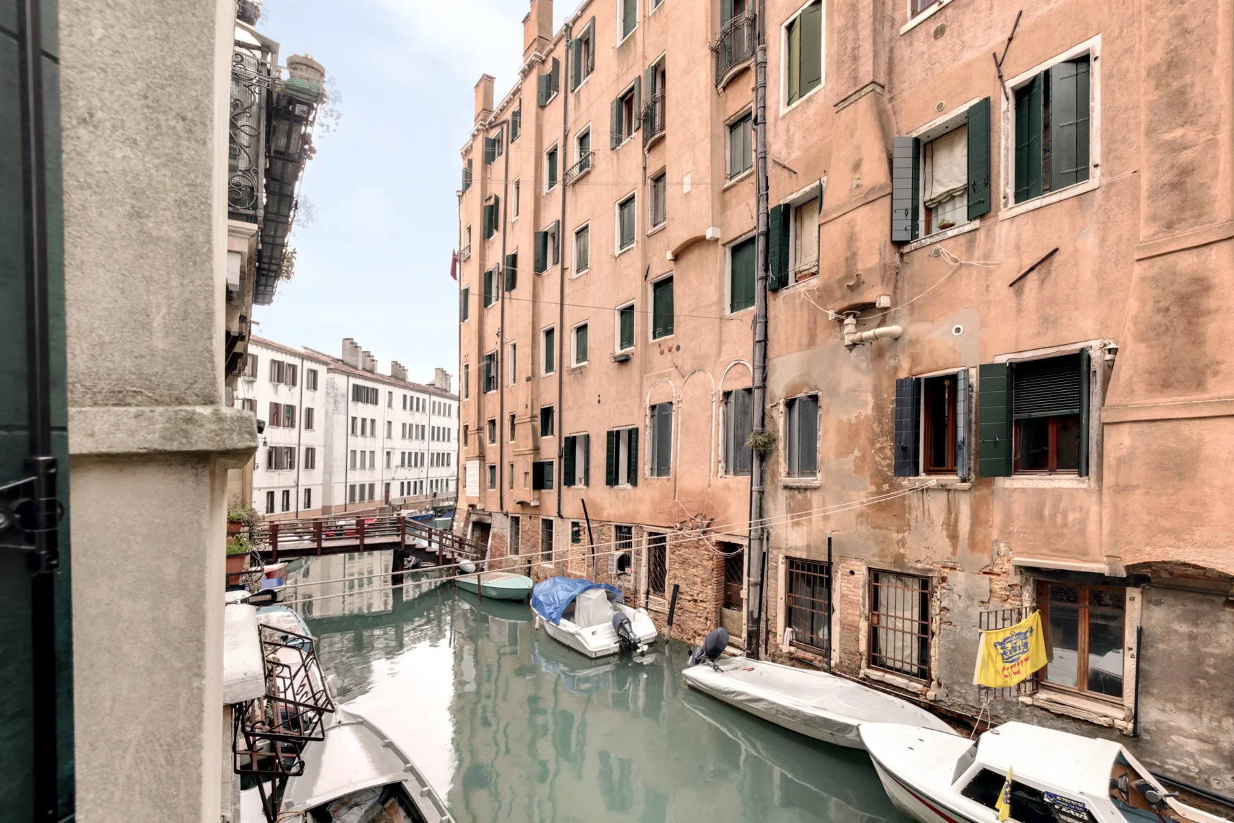 Un canal estrecho pasa entre edificios cercanos, con embarcaciones amarradas junto al agua.