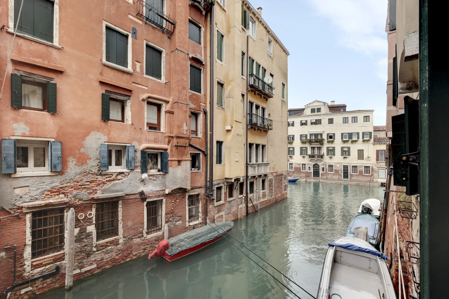 Un canal estrecho pasa entre edificios, con embarcaciones junto al agua.