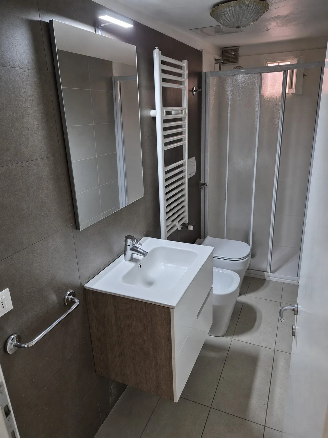 Un baño con lavabo, espejo y ducha de cristal.