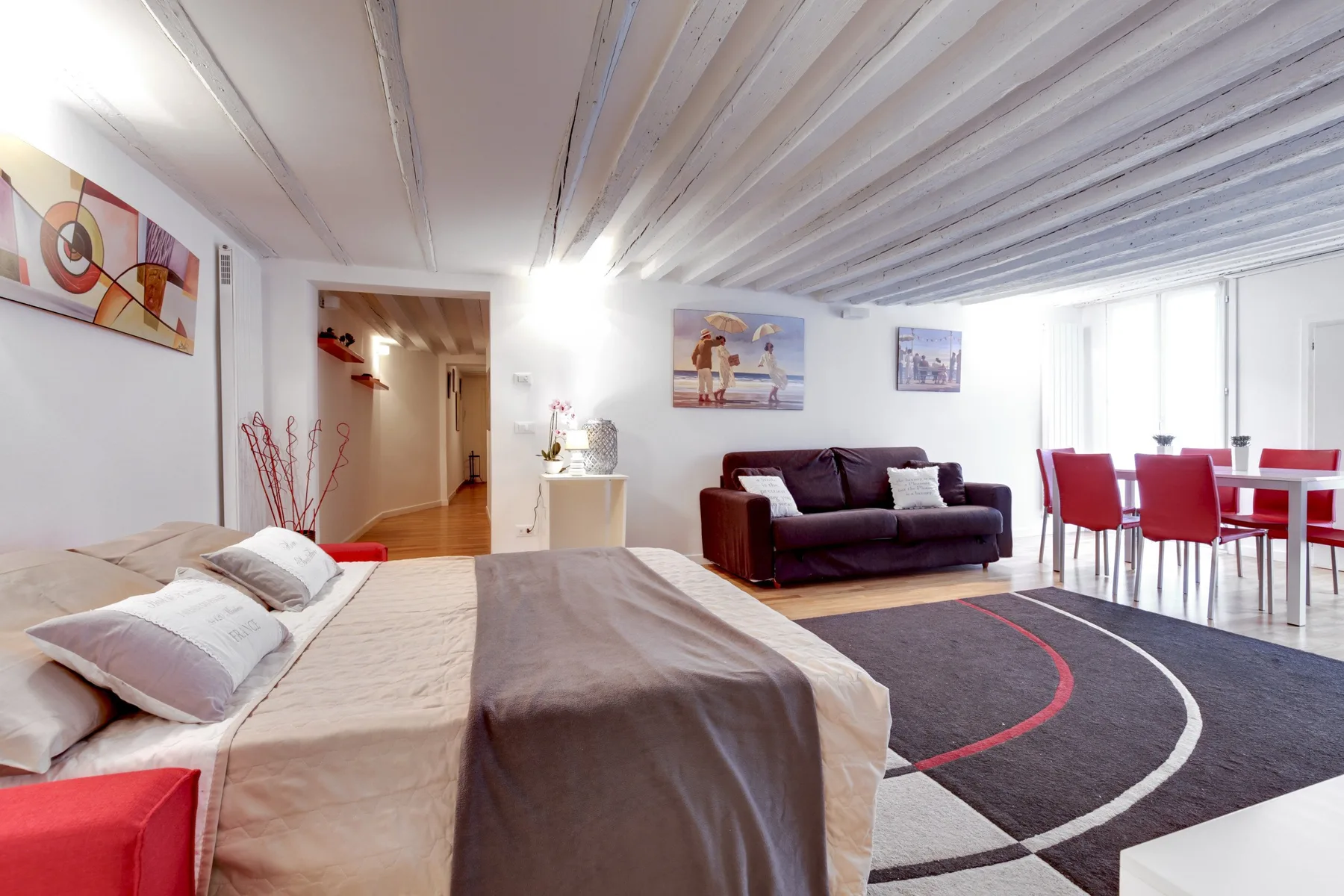 Un dormitorio combinado con sala de estar, cama, sofá y mesa de comedor.