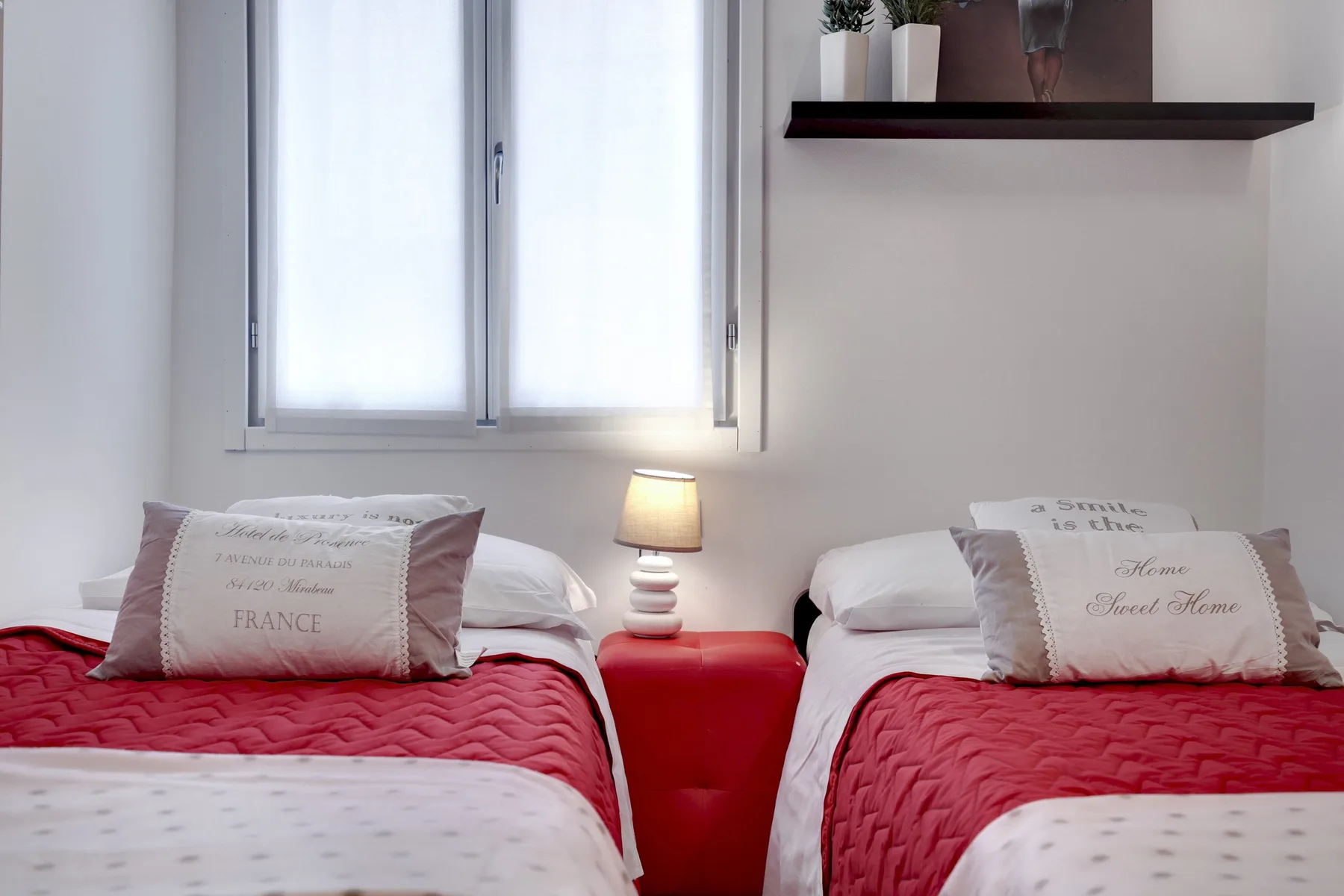 Un dormitorio con dos camas cubiertas de rojo junto a una ventana.