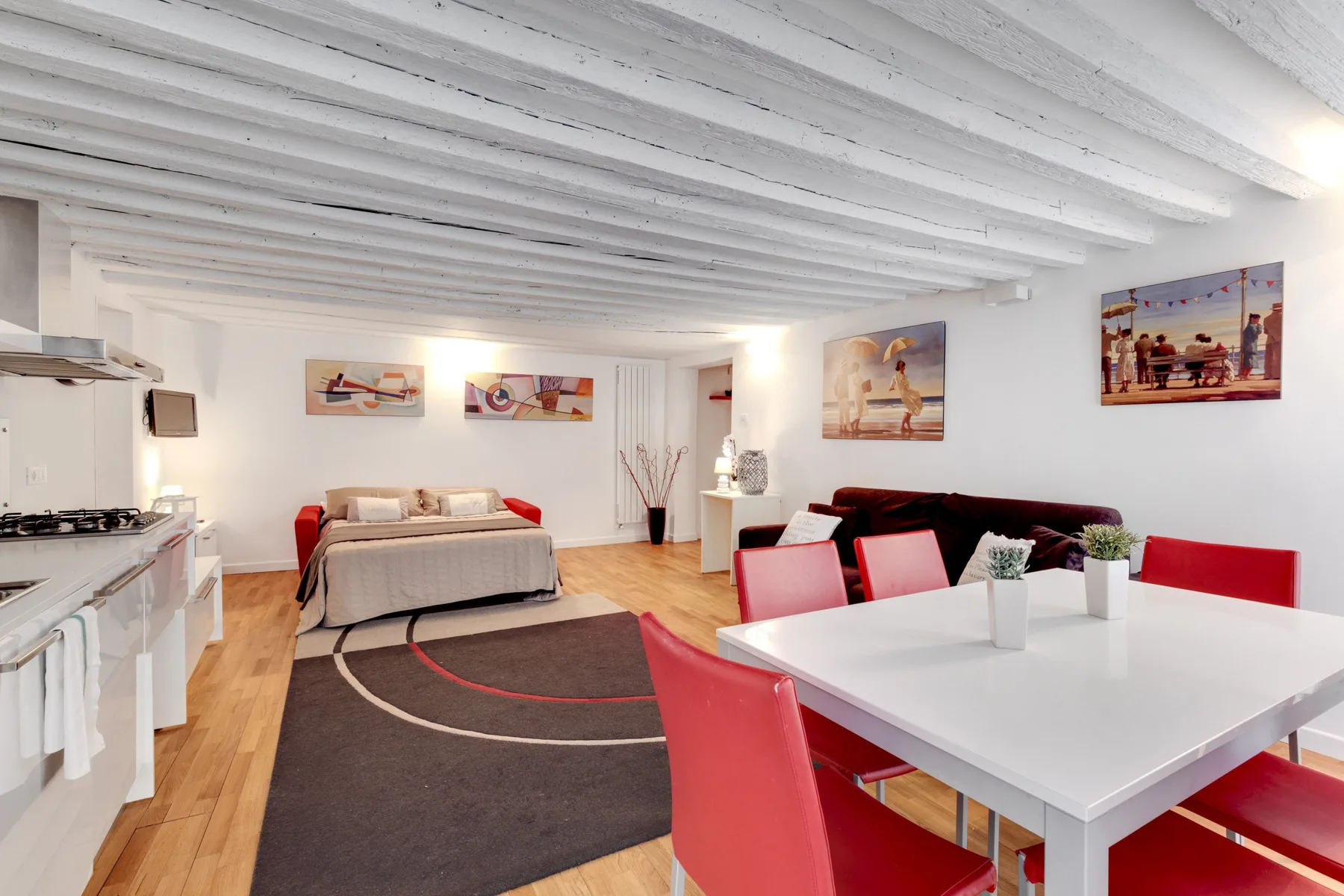 Un espacio abierto con dormitorio y comedor, cama y mesa blanca.