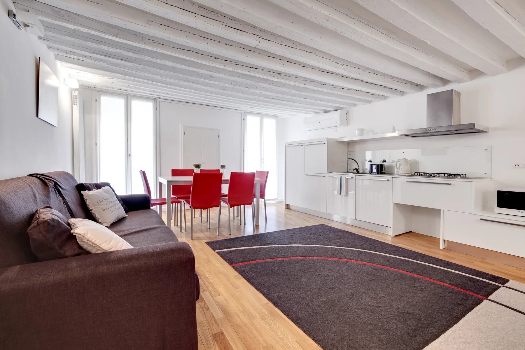 Una luminosa sala-comedor de planta abierta con cocina y sillas rojas.