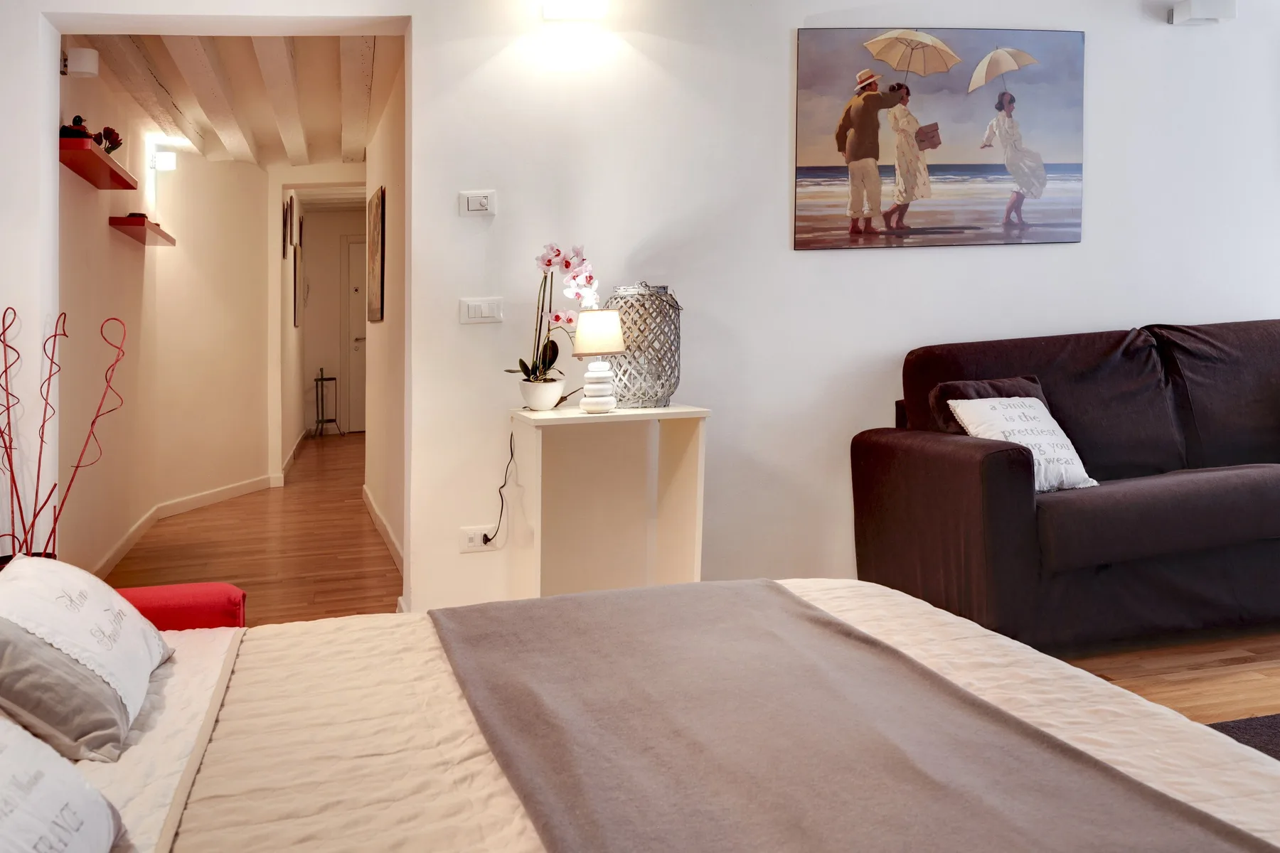 Un dormitorio con una cama junto a un sofá oscuro y una mesita.