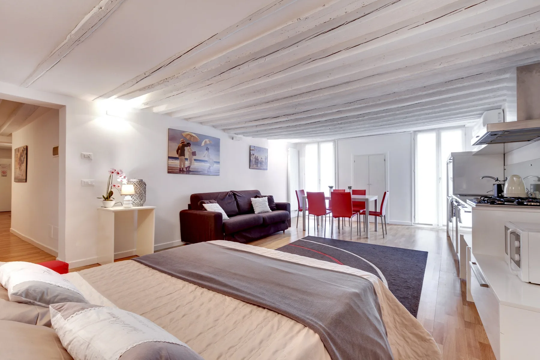 Un dormitorio y zona de estar con cama, asientos y mesa de comedor.