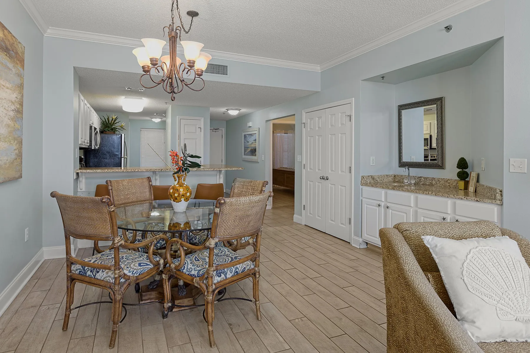 A dining area with a glass table and seating, beside a counter and storage cabinets.