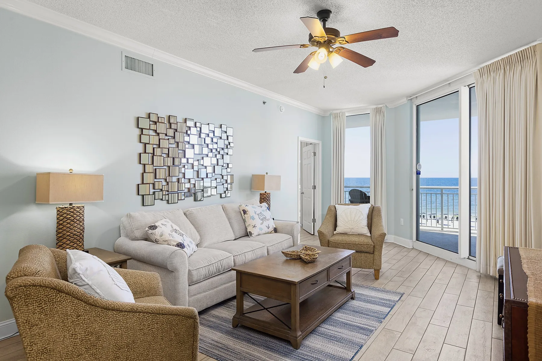 A living room with seating, a coffee table, and glass doors overlooking the water.