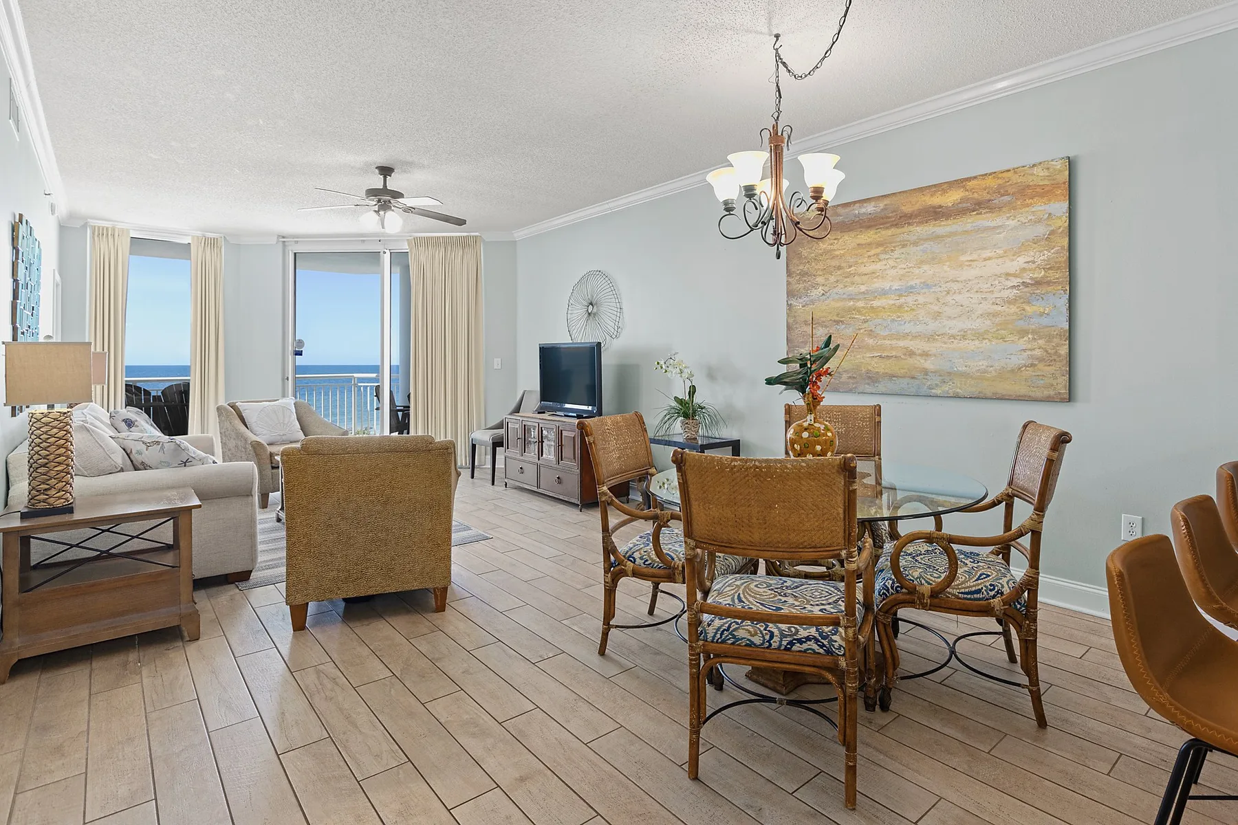 A living and dining area with seating, a glass dining table, and ocean views through the windows.