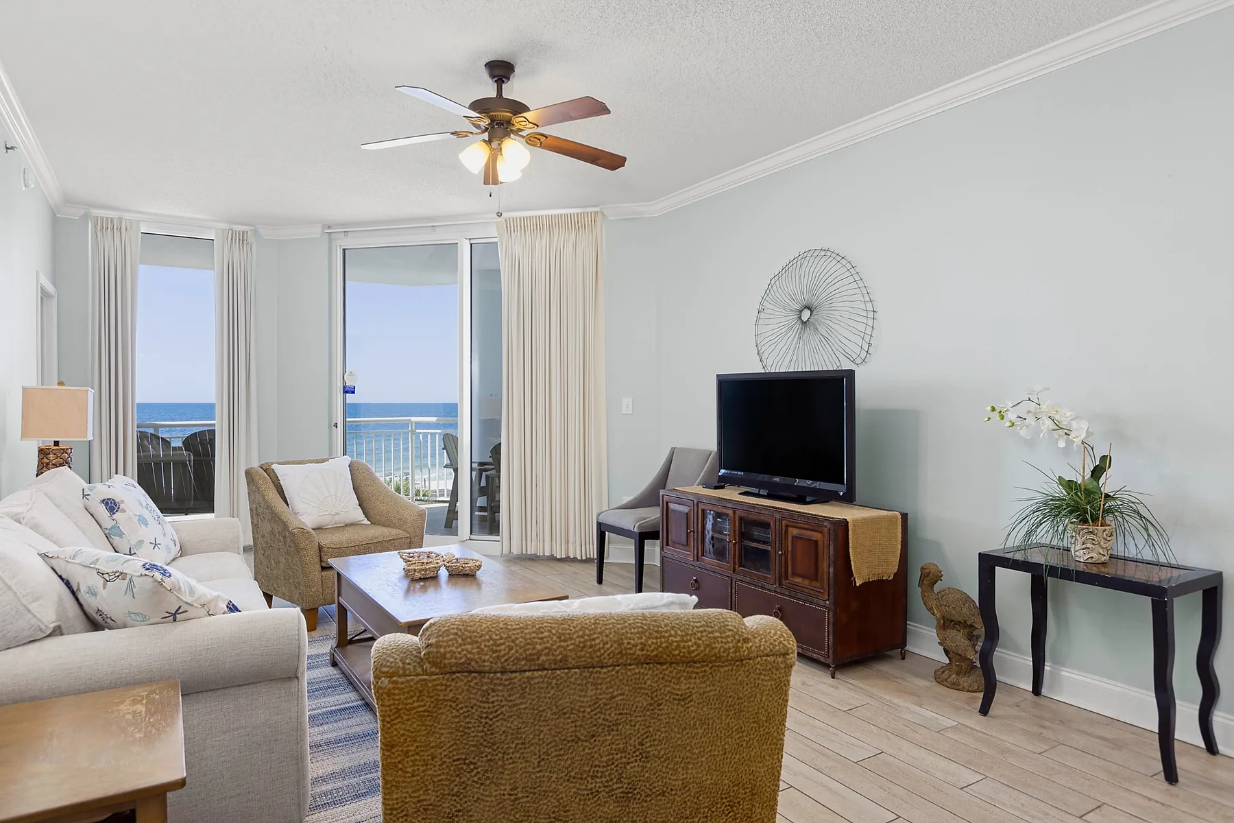 A living room with seating, a television, and windows overlooking the ocean.
