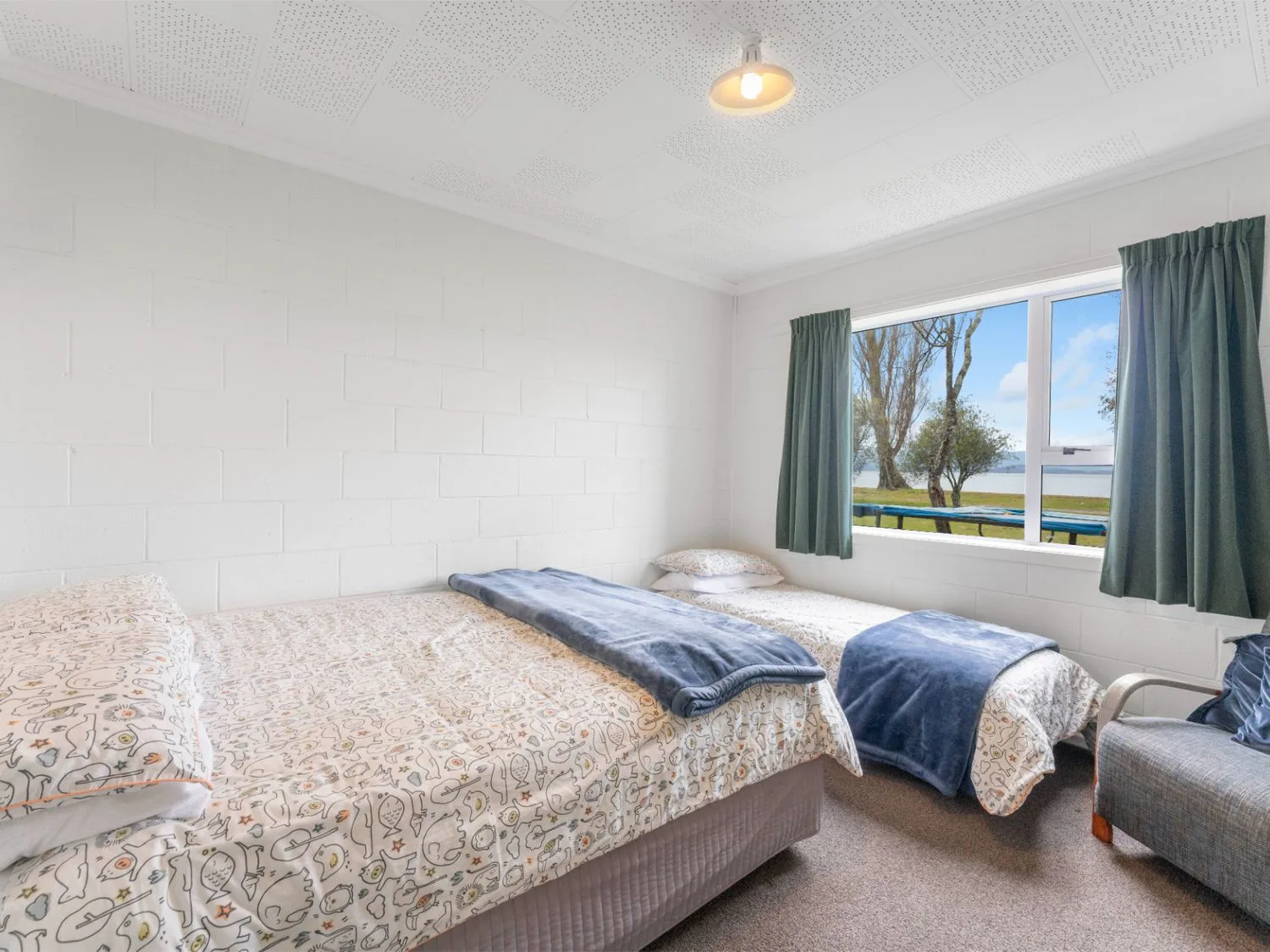 Un dormitorio con dos camas y una ventana con vistas a árboles.