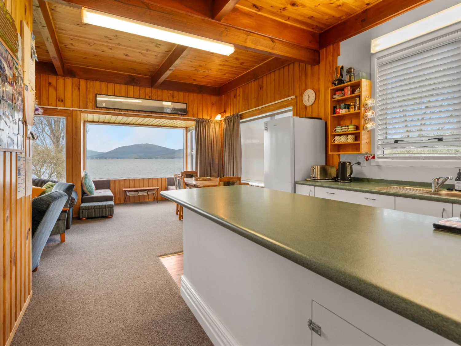Cocina y sala de estar con una encimera larga y vistas al lago por la ventana.