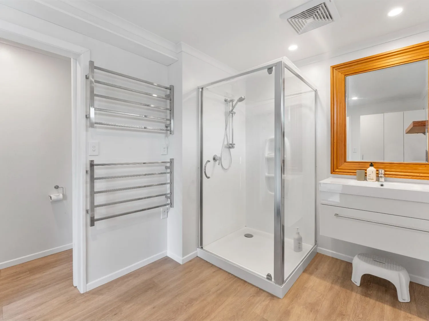 Un baño luminoso con ducha de vidrio y tocador.