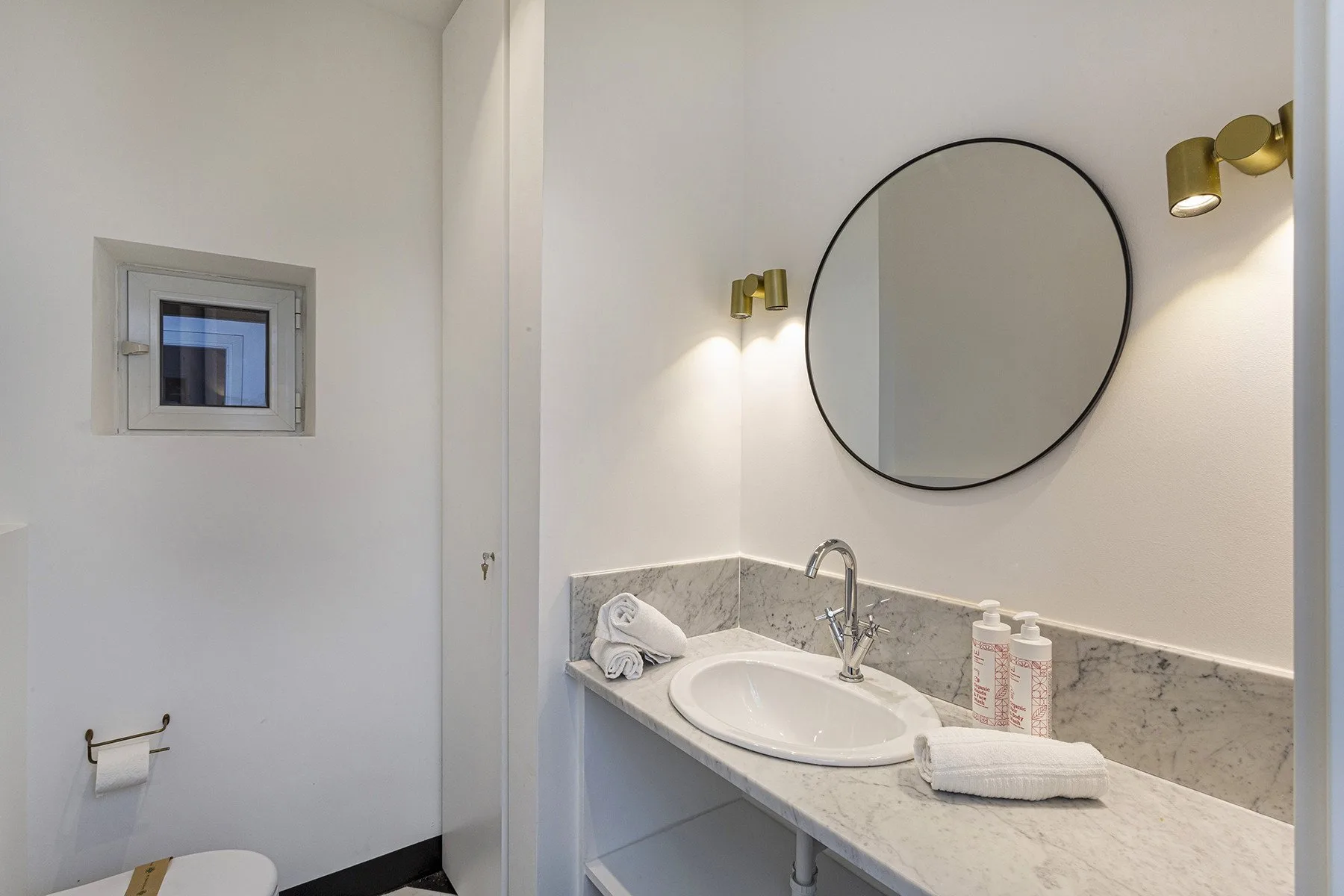 Un lavabo de baño con espejo redondo y luces de pared.