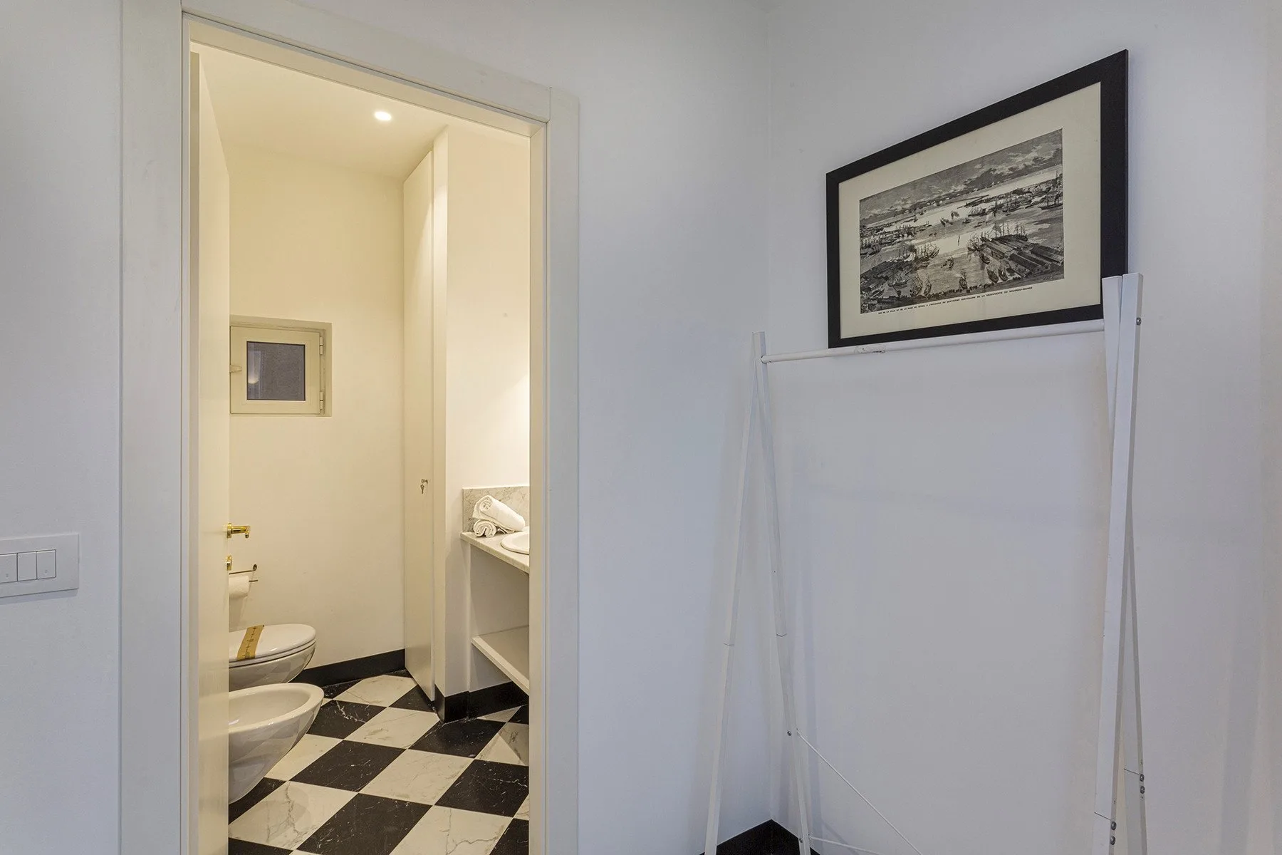 Un baño con suelo ajedrezado en blanco y negro y un lavabo.