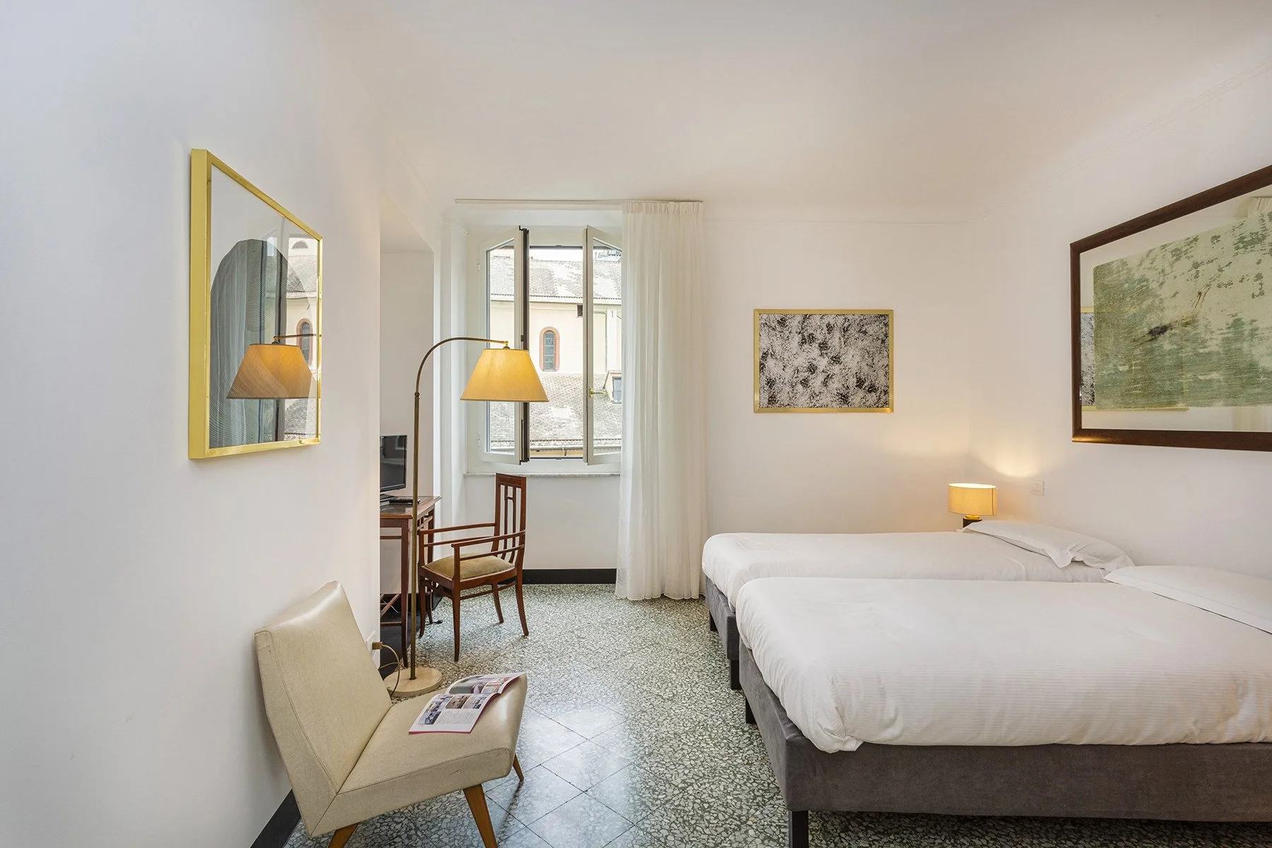 A bright bedroom with a double bed, a chair, and a window.