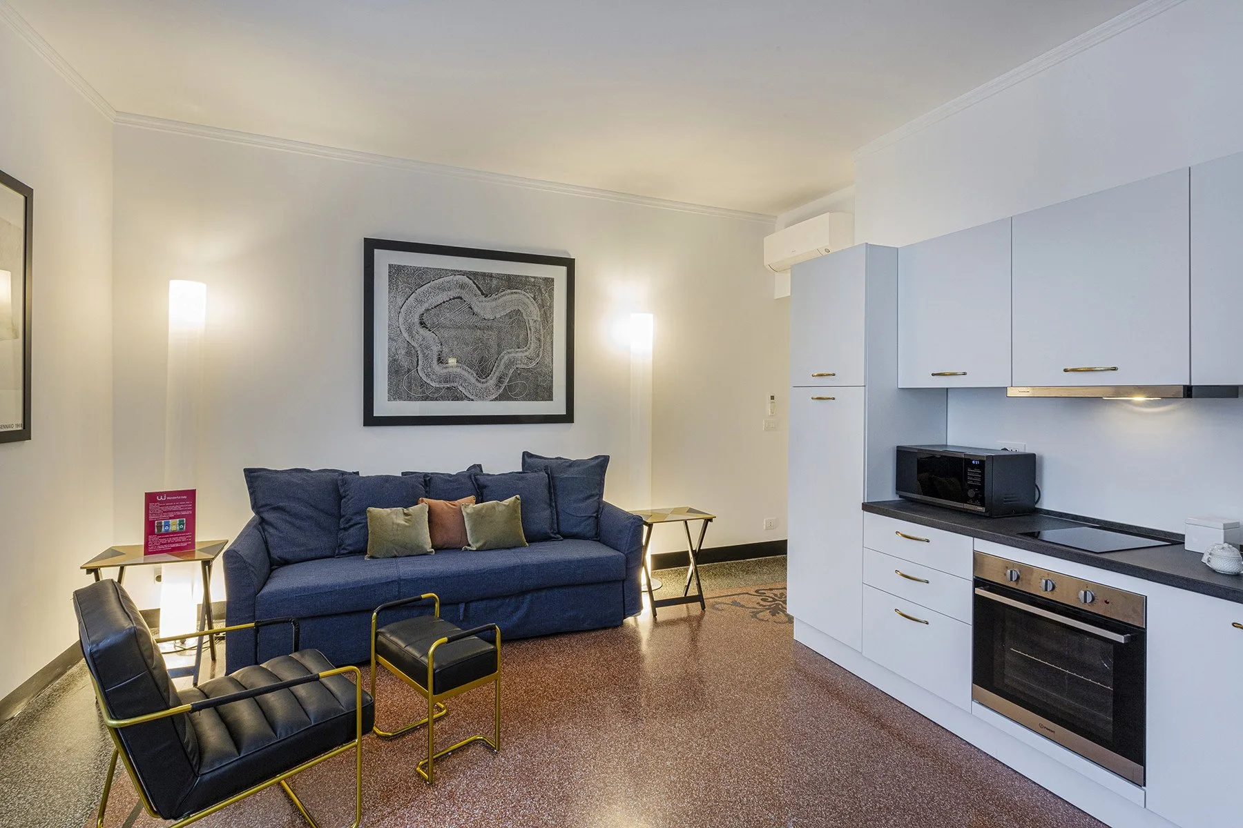 A living room with blue seating and a kitchen area.