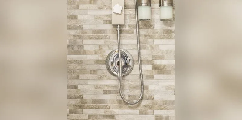 A shower with a handheld showerhead against a tiled wall.