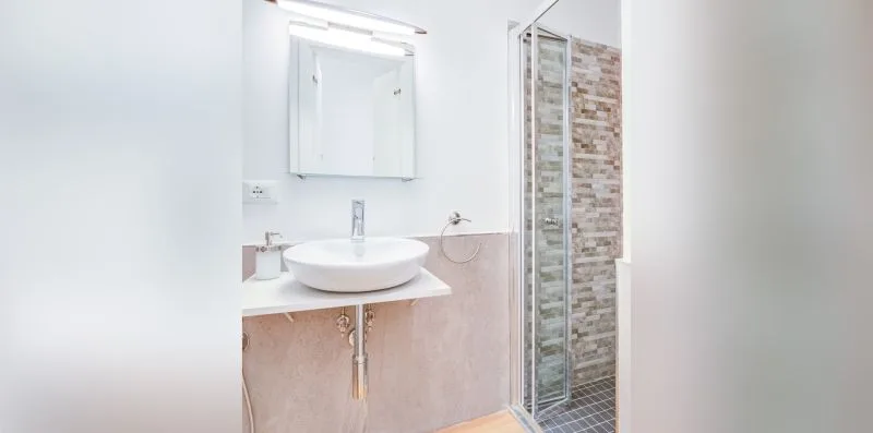 A bright bathroom with a vessel sink and glass shower.