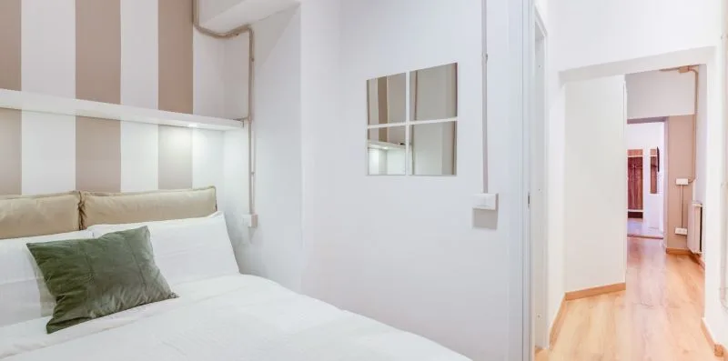 A bedroom with a bed, striped wall panels, and an open doorway.