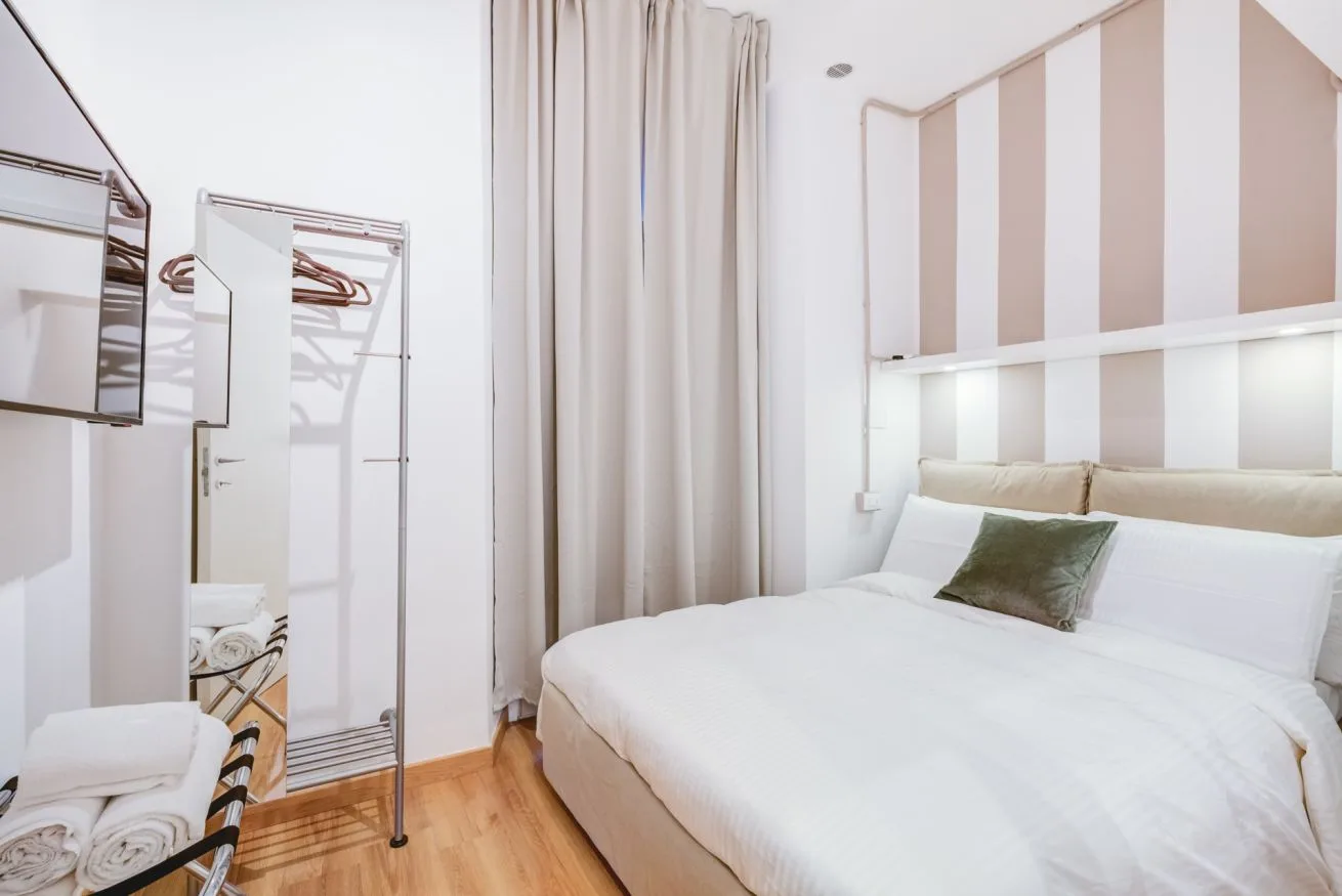 A bright bedroom with a neatly made bed and striped wall.