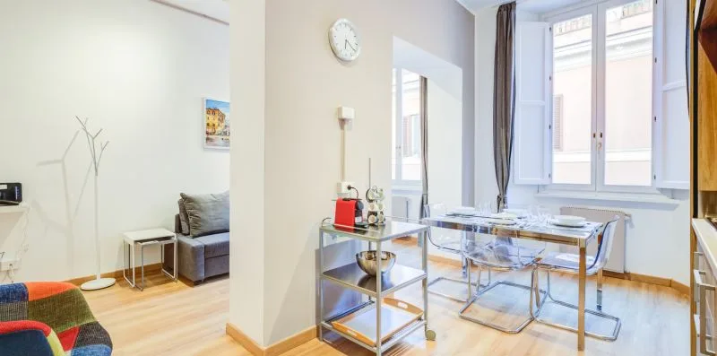 A bright living and dining area with a glass table and seating.