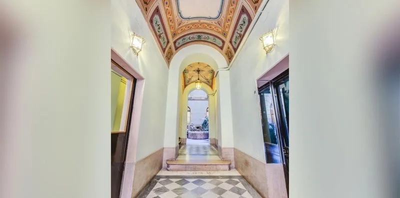 A decorated interior hallway with an arched doorway and patterned ceiling.