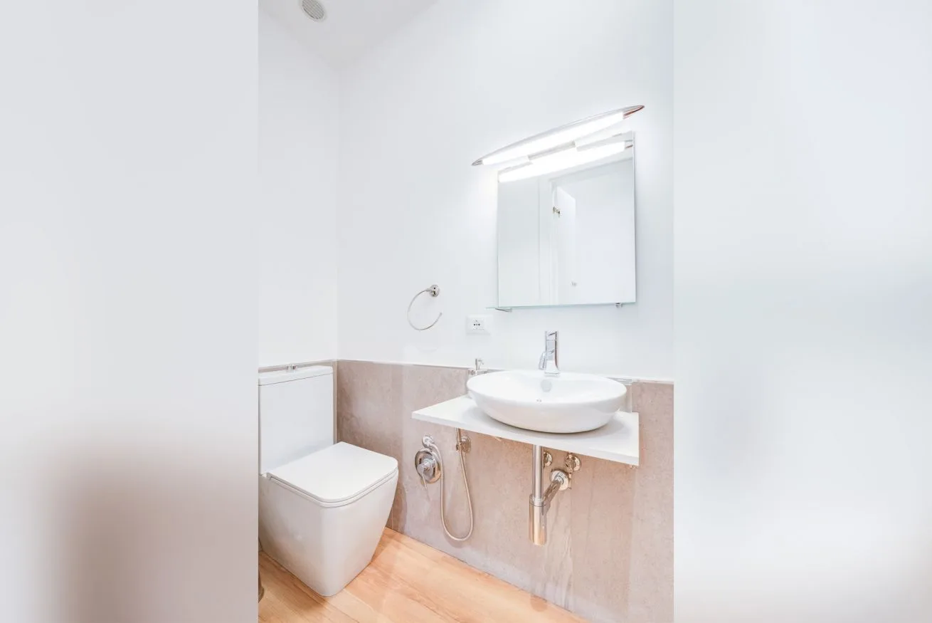 A bright bathroom with a wall-mounted sink and mirror.
