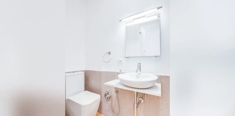 A bright bathroom with a sink, mirror, and toilet.