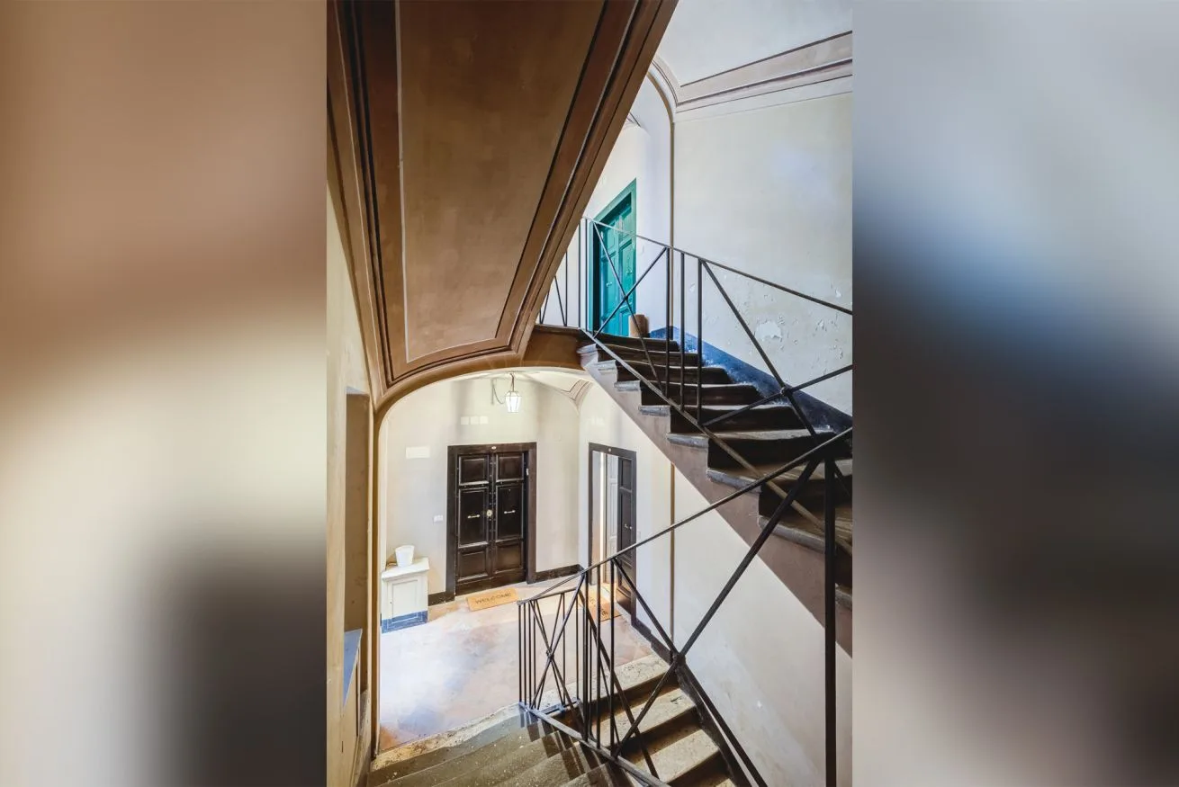 An interior stairwell with dark steps and black metal railings.