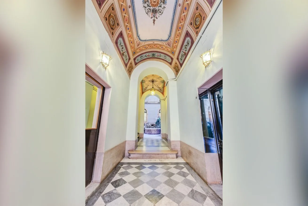 An ornate interior hallway with a patterned ceiling and tiled floor.